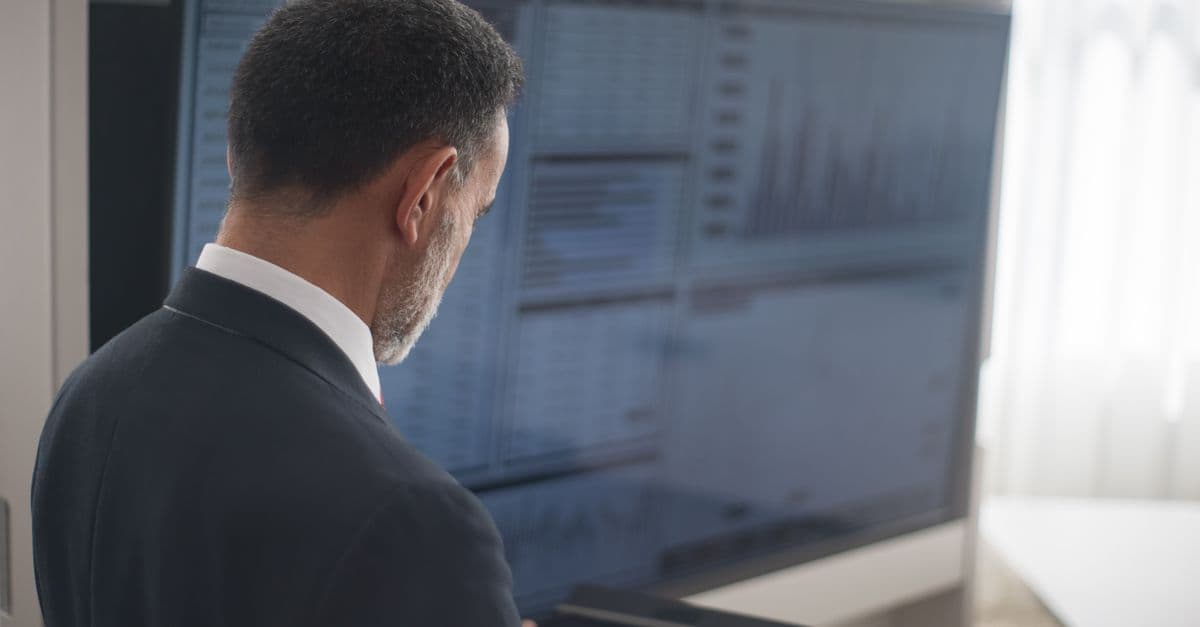 Profissional analisando os mercados financeiros em um tablet digital em um ambiente de escritório moderno.