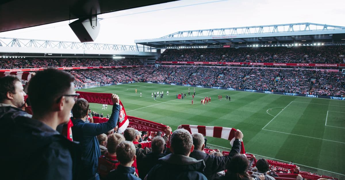 Torcedores torcem enquanto os jogadores entram em campo em um vibrante estádio de futebol, criando uma atmosfera elétrica.